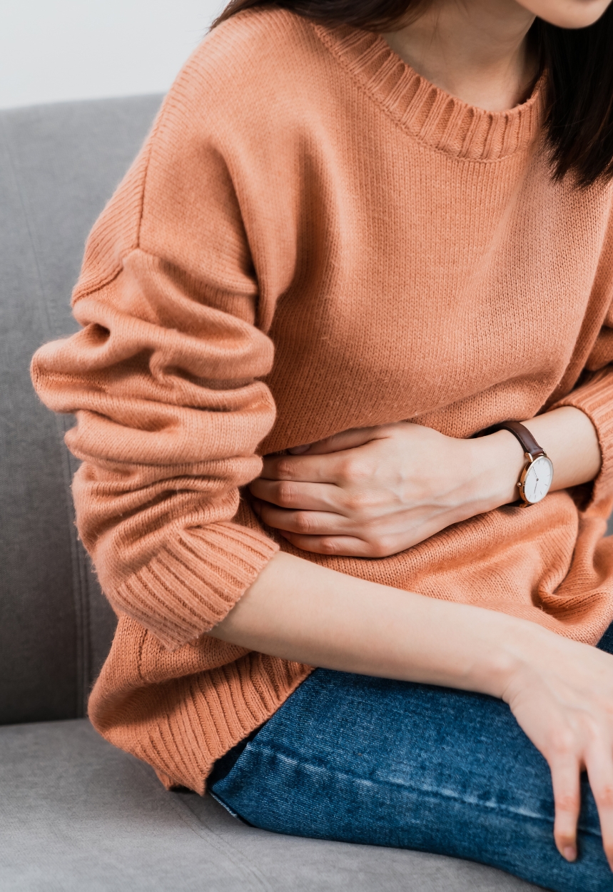 Eine Person hält sich mit der linken Hand den Bauch